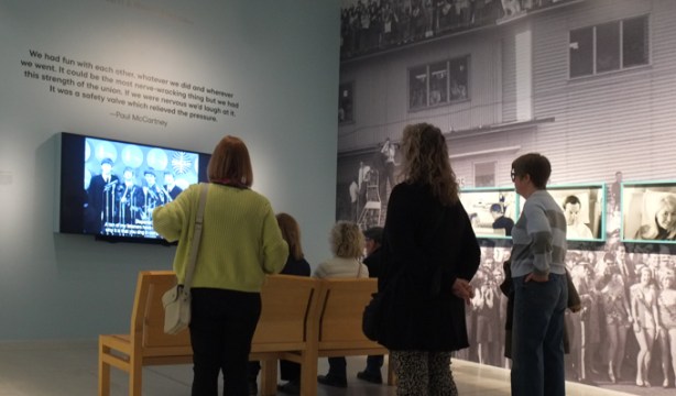 people at Art Gallery of Ontario watching a video of the interview with the Beatles at the airport in New York City when they first arrived in the USA