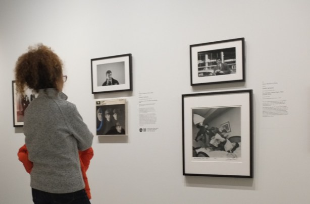 a woman looking at black and white photos on the wall of an art gallery