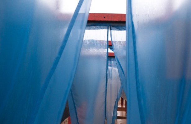 blue flaps of lightweight fabric hanging from red wood supports in public art installation