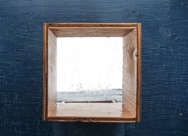 small window in dark blue plywood wall, looks towards lake ontario
