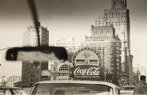 photograph taken out the front window of a car of a New York City scene with billboards and tall buildings