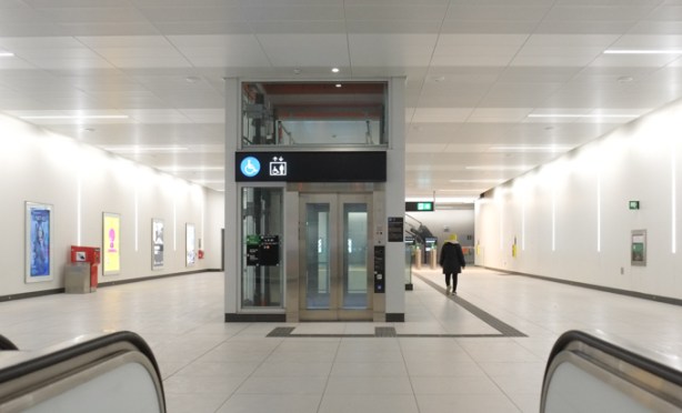 interior of Eglinton LRT subway station, upper level, with elevator inthe middle, white floor, white walls, and white ceiling