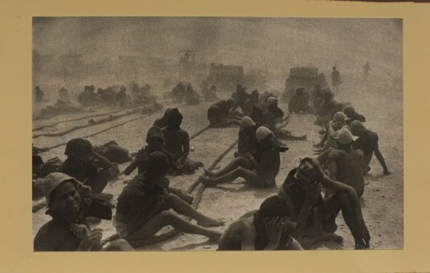 black and white photo on gallery wall by Ernst Haas, on set during production of film 'Land of the Pharaohs', people sitting on ground, very dusty with dust in the air