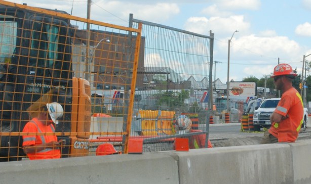 workmen at construction site, one is on his phone