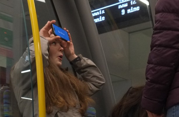 teenage girls playing games with phone onthe streetcar