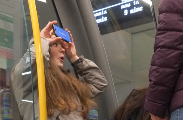 teenage girls playing games with phone on the streetcar