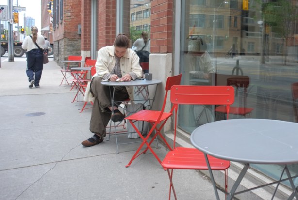 women sitting at table and red chairs outside black canary coffee shop on Sherbourne street