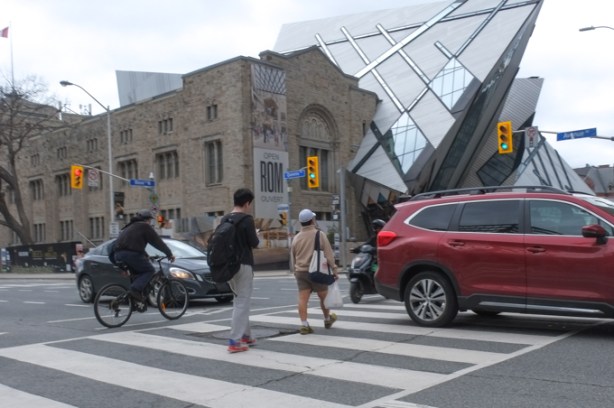 Avenue Road and Bloor intersection, in front of the ROM, people crossing on green light, car stopped in intersection