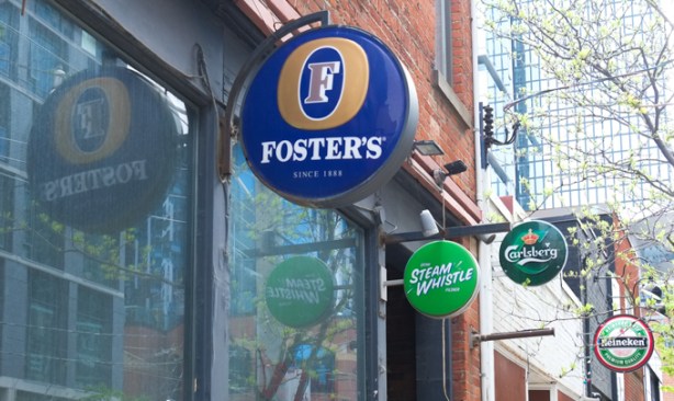 round beer signs above the windows of old pubs, now empty, Fosters, Steam Whistle, Heineken, and Carlsberg