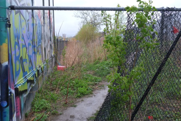 a hole in the fence beside train tracks