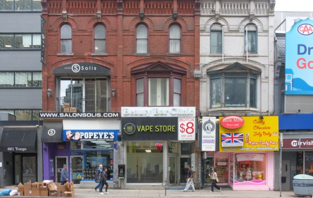 stores on Yonge Street, three storey red brick building with Popeyes and a vape shop, beside painted brick building with British candy store, jelly belly candies