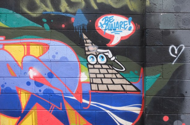 part of a mural in Milky Way, triangle shape with two eyes and words be aware!