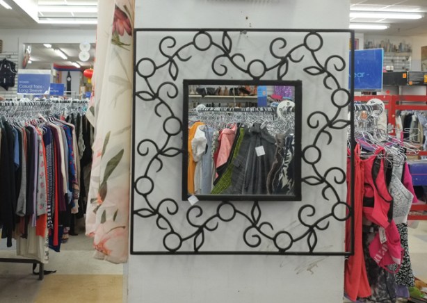square mirror on a wall in a thrift store