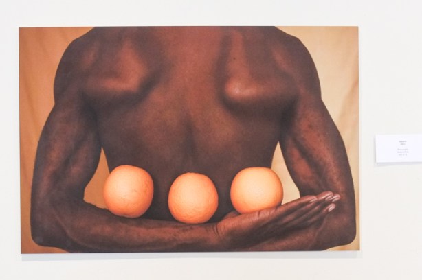 photography exhibit, by Jamaal Owusu-Ansah, back of black man holding three oranges behind his back