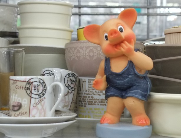 small plastic pink pig wearing denim short overalls