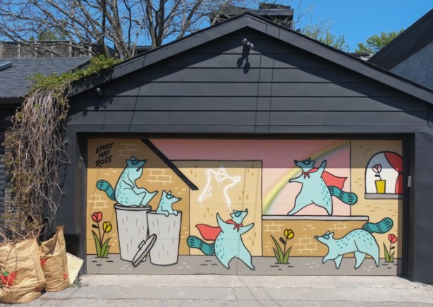 Emily May Rose mural of raccoons on a garage door in an alley
