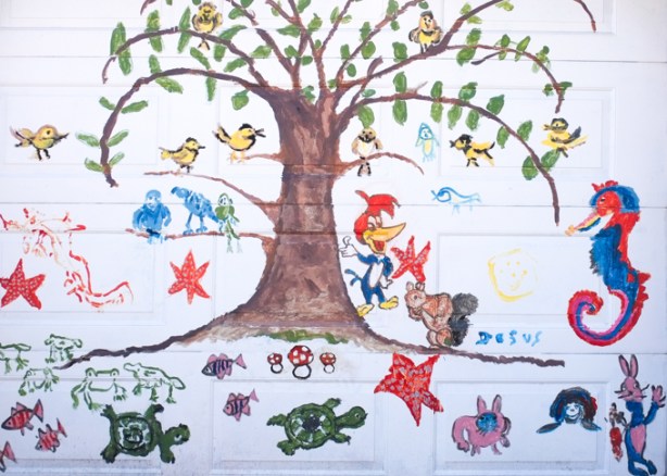 childlike drawings on white grage door - tree with yellow birds on branches, a seahorse, some turtles,