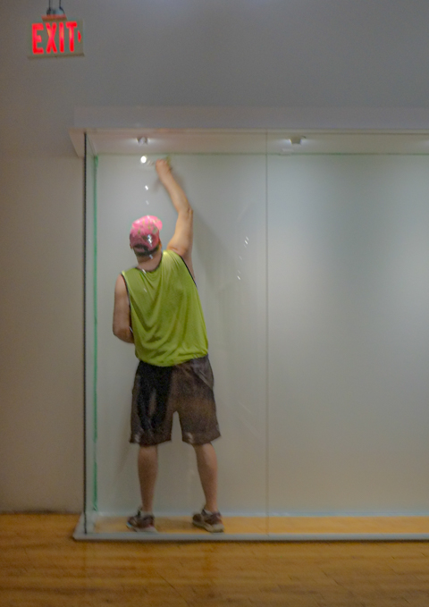 a man is standing inside a display case, adjusting the overhead lights