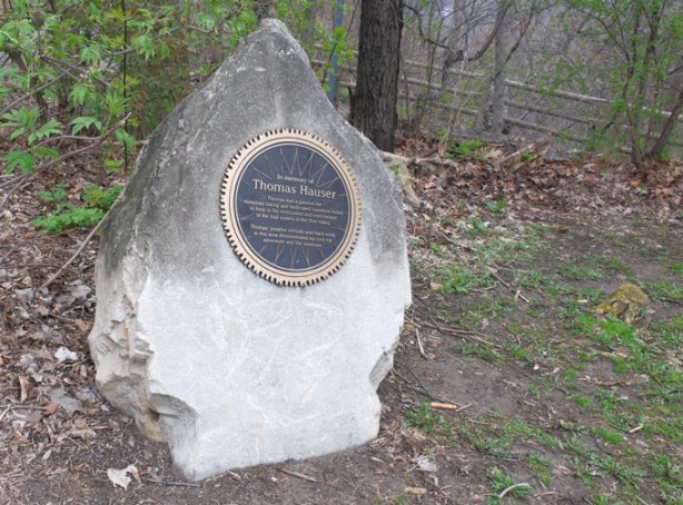 circular, like a bike wheel, plaque mounted on a large rock at the start of a trail, in memory of Thomas Hauser