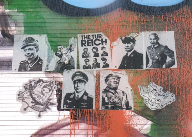 paper paste up graffiti on a glass wall beside railway tracks