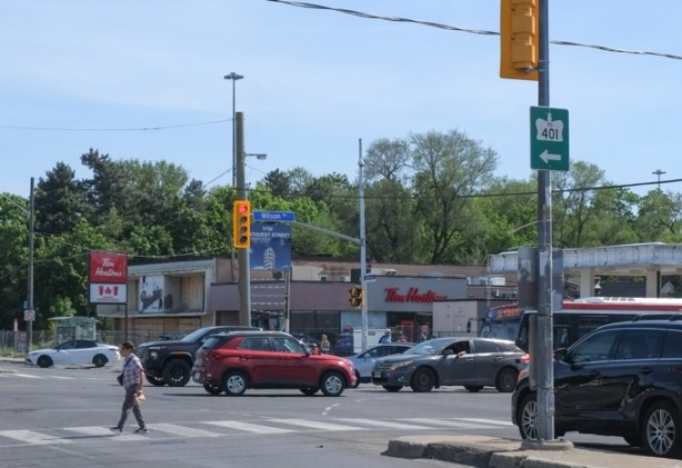 looking southwest at corner of Bathurst and Wilson, pedestrian crossing the street, some traffic, Tims in the background