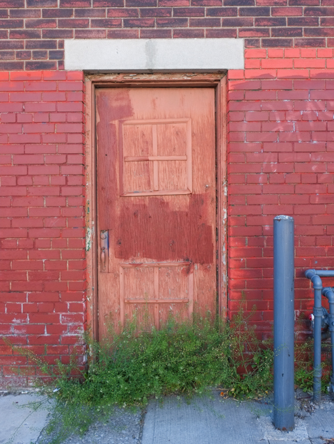 orange and red blotchy door, red brick wall,