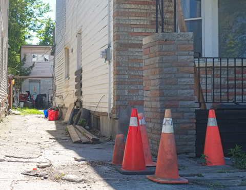driveway between houses, orange cones around corner of one of the houses, garage in the back