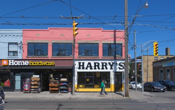 Harrys Burgers restaurant and a Home Hardware store on the northeast corner of Coxwell and Gerrard