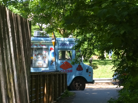 looking down a path in a ravine to the street where an ice cream truck is parked