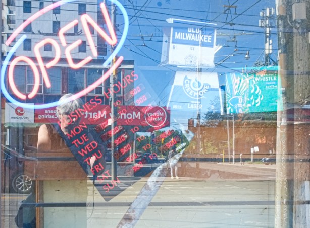 open sign in window, opening times sign with red letters, Boxes of old milwaukee beer and creemore beer signs inside the store