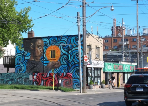 mural by flips and rowell soller on the side of Pizza Nova on Coxwell Ave