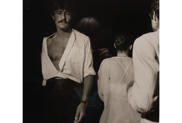 black and white photo by Larry Fink from his Social Graces series from the 1970s, young man with mustache, wearing a white shirt with buttons undone and bare chest is showing