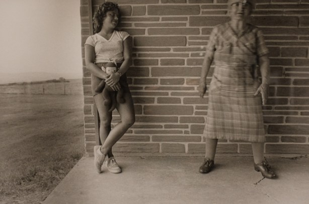 black and white photo by Larry Fink from his Social Graces series from the 1970s, two women standing on a concrete front porch, young woman in shorts, older woman in a plaid dress