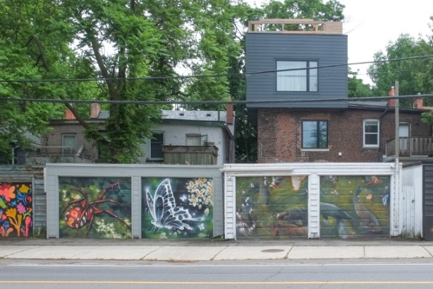 four garage doors in a row, all with street art murals, a spider, a butterfly and two with fish