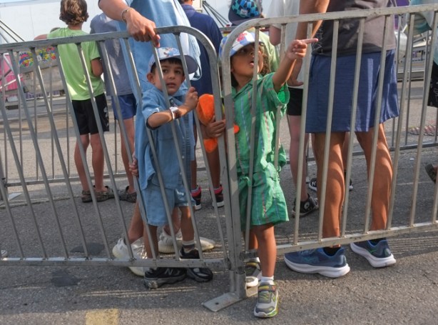 two boys standing behind metal barricades