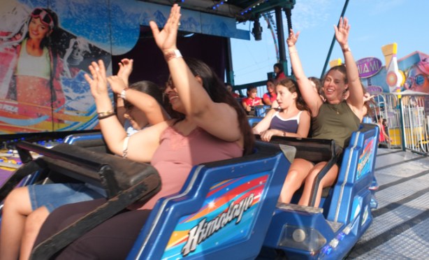 people on himalaya ride at the ex, going fast around a big circle, arms up, laughing