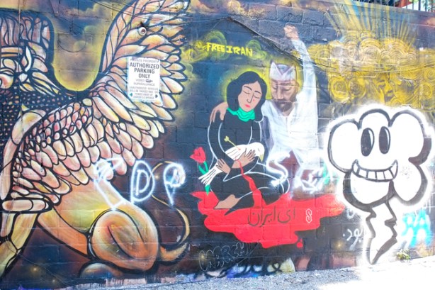 free iran mural in graffiti alley, woman holding a white dove that died because shot with an arrow