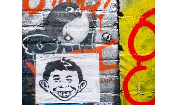 Alfred E. Neuman as a graffiti sticker, along with a black and white little bird
