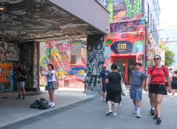 graffiti alley, people taking pictures, people walking past