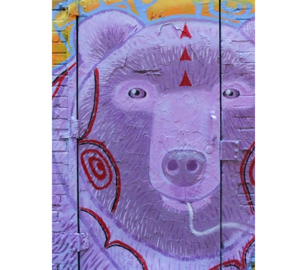 street art painting covering a door in graffiti alley, a large purple bear's head and face