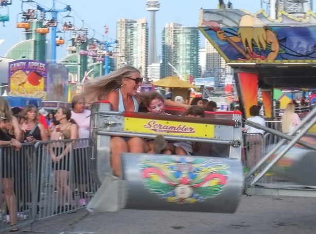 mother with very long hair, and two younger kids riding on the scrambler ride at the Canadian National Exhibition, midway