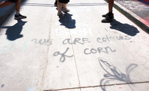 feet on paved alley, where someone has written we are the colour of corn