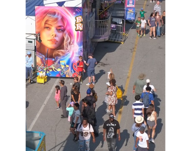 large sign with image of young woman's portrait, people walking past it