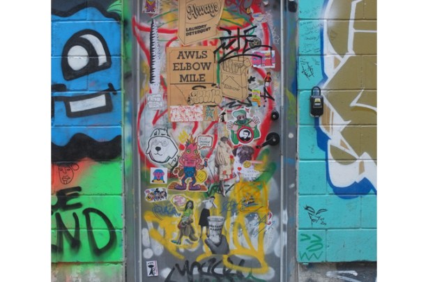 collection of graffiti slaps covering a door in graffiti alley