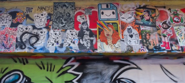 many paste ups up high on a wall