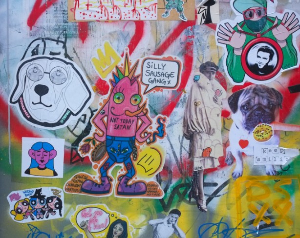 part of a door covered with graffiti stickers and other slaps