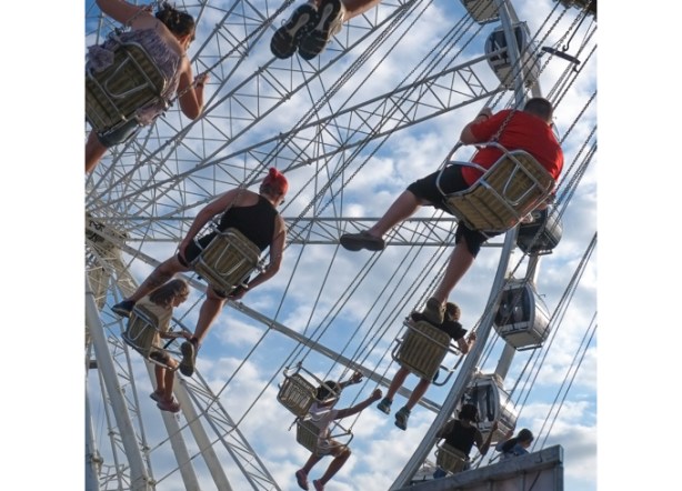 viewed from below, people on swing that is elevated and going around in circles, a ride at the ex, canadian national exhibition