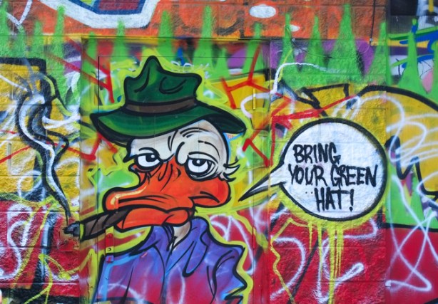 Donald Duck like character, but older and seedier, with black hat, text balloon that says bring your green hat 