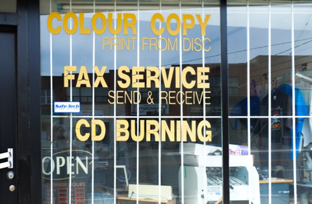 signs in store window advertising CD burning service, also fax machines, 