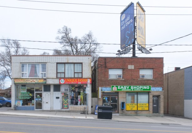 two brick two storey commercial buildings on Eglinton west, one with a large billboard on the roof, Easy Shoping Discount and Variety, and Unique 